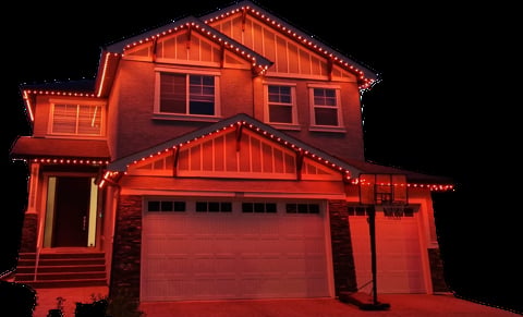Red brick two-story house illuminated with bright red LED lights against a dark night sky